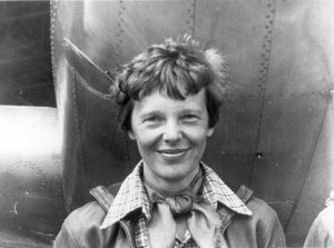 Amelia_Earhart_standing_under_nose_of_her_Lockheed_Model_10-E_Electra_small-300x223.jpg