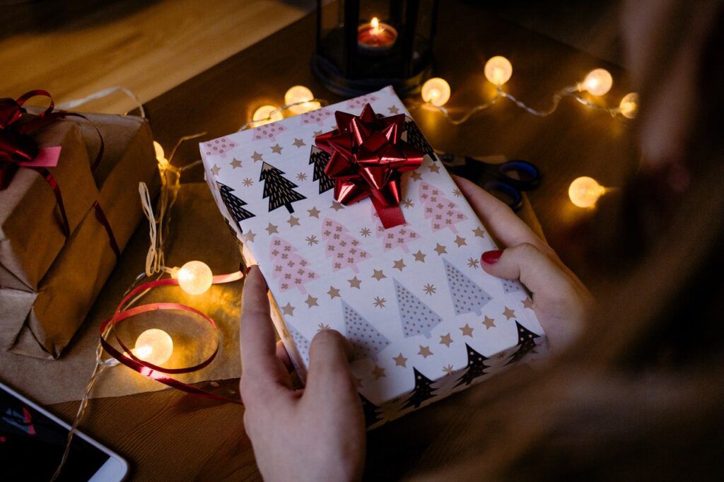 person-holding-gift-box-with-red-ribbon-beside-string-lights-1687049-1024x682.jpg.optimal.jpg